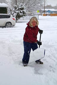 Woman shoveling winter snow off of a sidewalk in Boise, Idaho, USA.